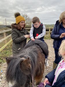 Child using Equihandee Core Support during equine therapy session with mum stood next to him